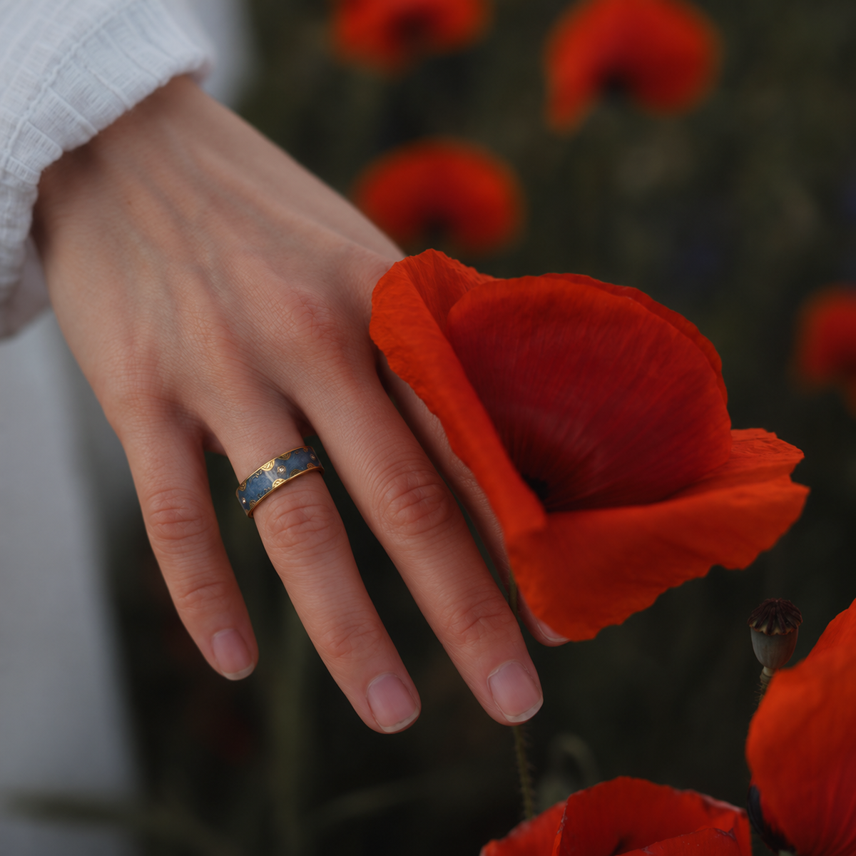 Retro Blue Smart Ring with gold accents worn on a woman's hand in a floral outdoor setting#color_retro-blue