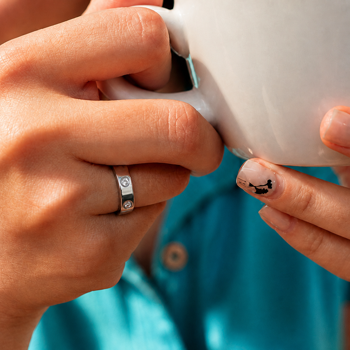 Close-up of a woman wearing the Wrongduck HR1 silver smart ring while holding a coffee cup#color_hr1-silver