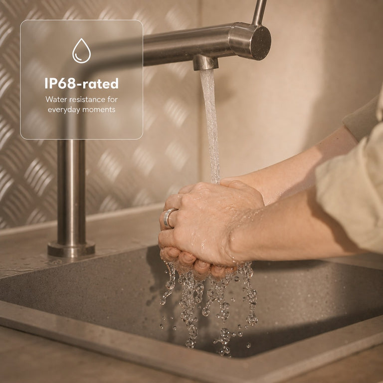 Hands wearing a silver smart ring under running water with an IP68-rated water-resistance note