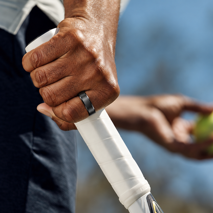 Close-up of a hand wearing a black SY15 smart ring while gripping a white racket handle