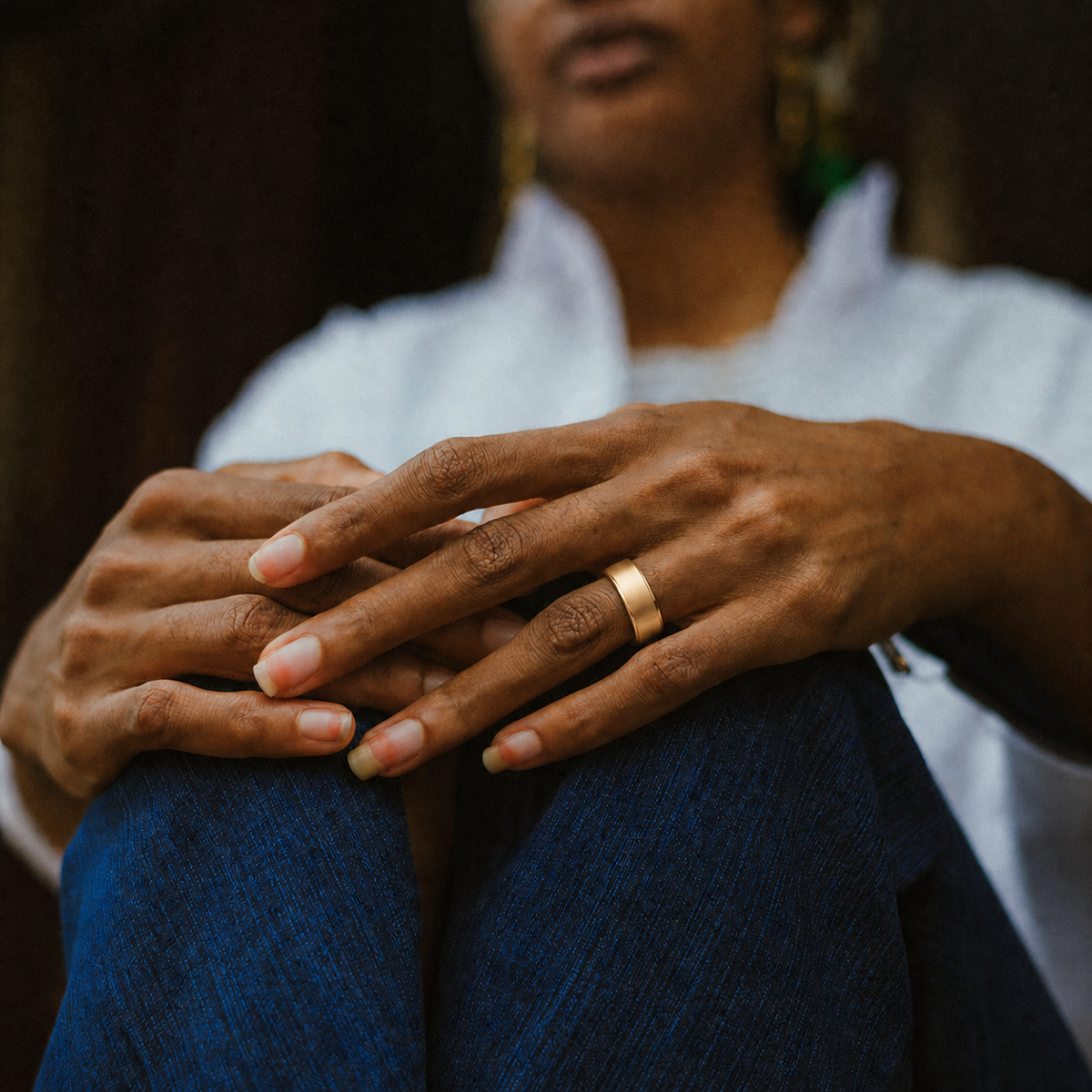 Woman wearing an R10 Gold Smart Ring with a brushed finish in a relaxed seated lifestyle setting#color_r10-gold