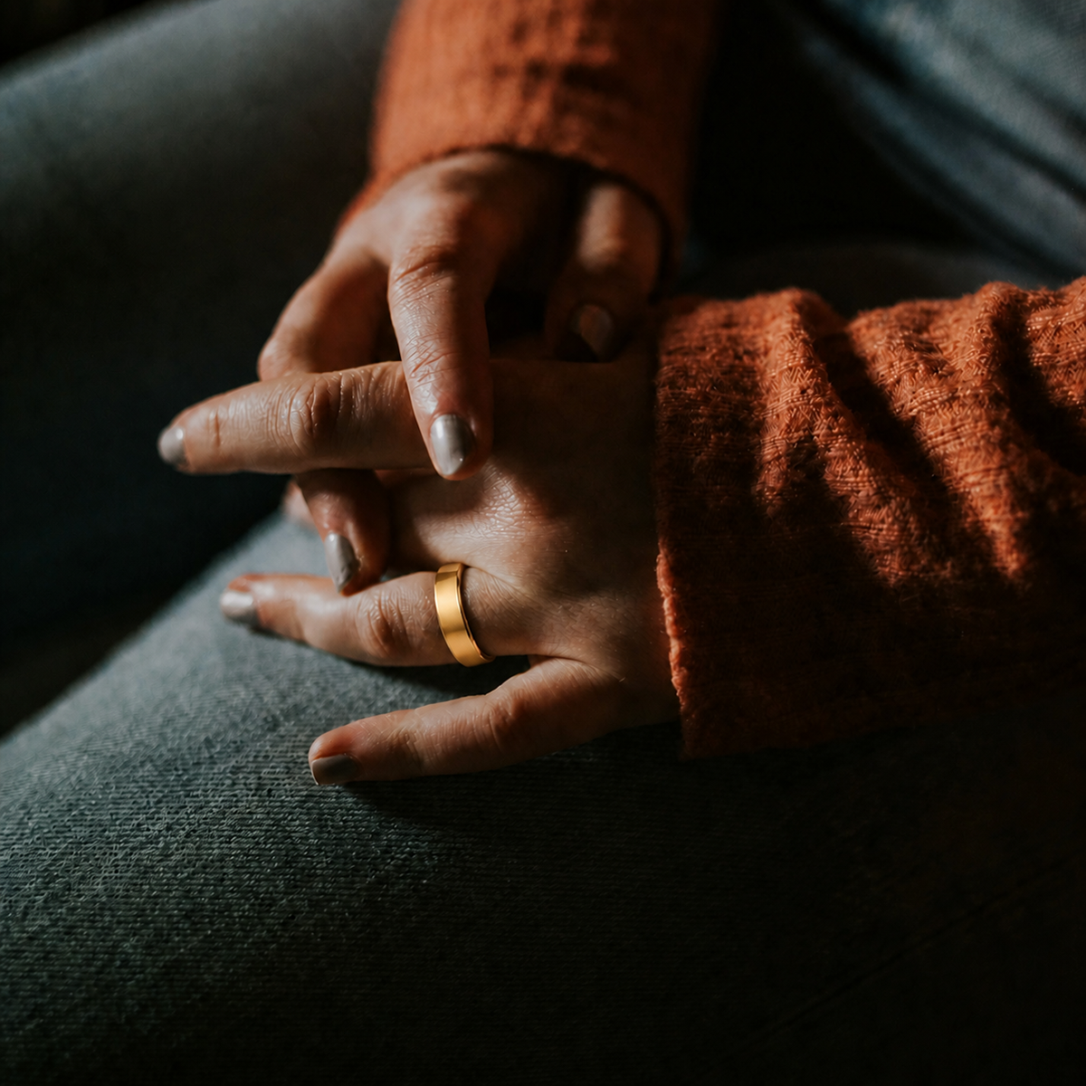 Close-up of an R10 Gold Smart Ring worn on a woman's finger in warm indoor light#color_r10-gold