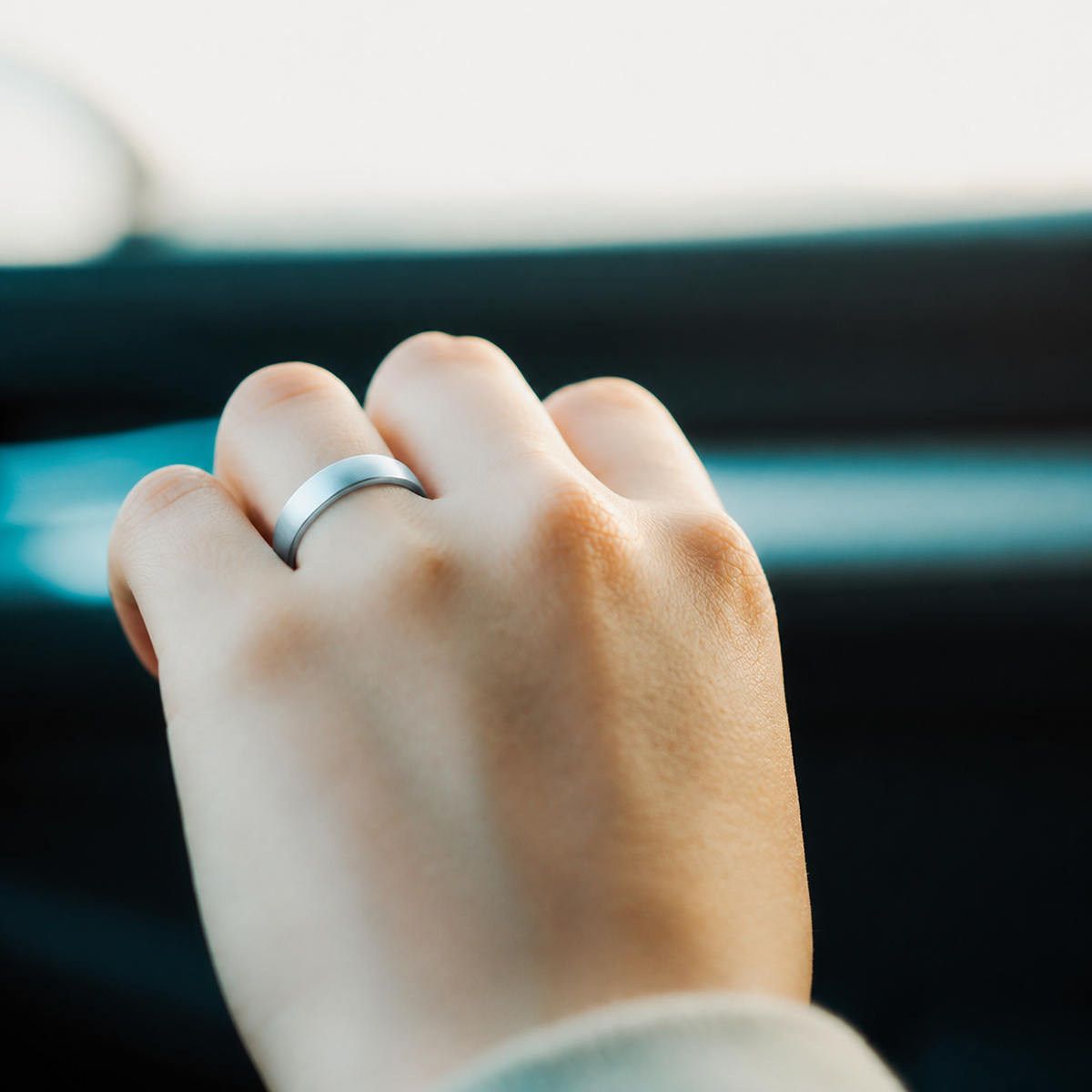 Close-up of R10 silver smart ring worn on a woman's finger in natural light#color_r10-silver