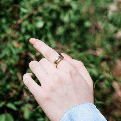 V6 Champagne Gold smart ring worn outdoors against green foliage with a pale blue sleeve#color_v6-diamond-gold