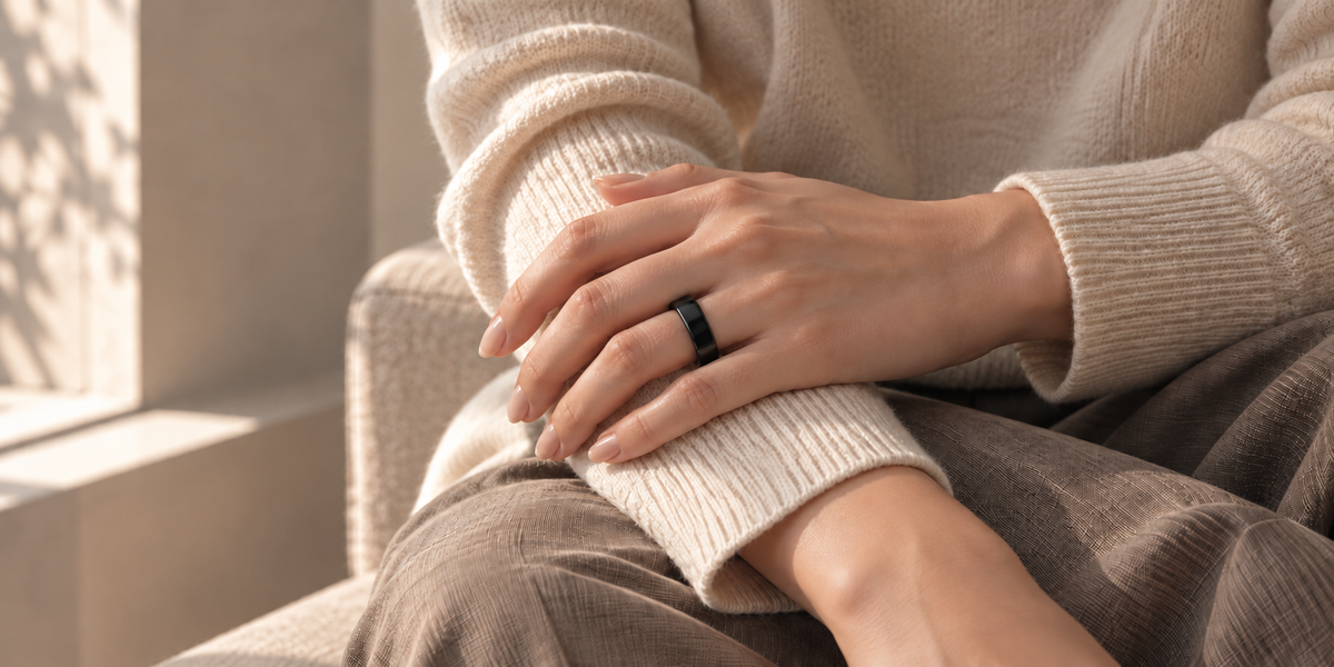 Woman wearing a plain black ring with an ivory knit sweater in warm window light