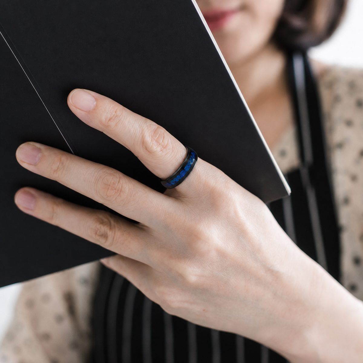 Close-up of a woman wearing the Wrongduck Galaxy smart ring while reading#color_galaxy