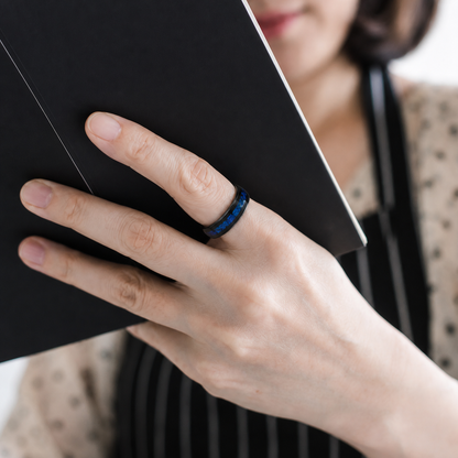 Close-up of a woman wearing the Wrongduck Galaxy smart ring while reading#color_galaxy