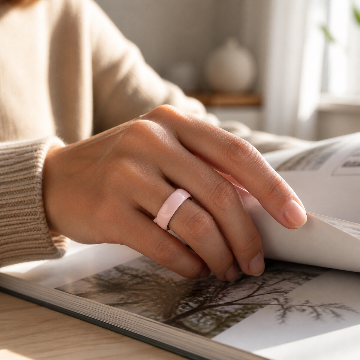 Woman wearing a pink ceramic smart ring while reading in natural window light #color_ceramics-pink
