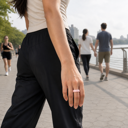 Woman wearing a pink ceramic smart ring while walking along a waterfront promenade #color_ceramics-pink